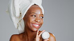 Face, product and beauty with a model black woman in studio on a gray background for skincare treatment. Portrait, towel and lotion with an attractive young female indoor to apply facial moisturizer