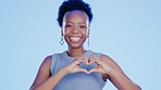 Happy, heart and face of a black woman in a studio with a positive, happiness and confident mindset. Happiness, smile and portrait of African female model with a love hand gesture by blue background.