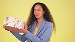 Business, woman and shake box in studio isolated on a yellow background for birthday. Gift, present and face portrait of happy, smile or young female shaking trying to guess what is inside or curious