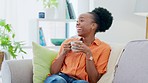 Coffee, remote control and black woman relax on sofa laughing, watching and streaming in her home. Comic, entertainment and lady on a couch with tea, positive and chilling in a living room on day off