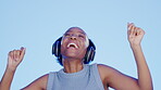 Music headphones, dance and black woman singing in studio isolated on a blue background. Singer, happy and dancing female with headset for streaming, listening and enjoying podcast, radio or song.