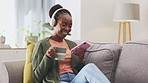 Coffee, phone and black woman relax with music on sofa, happy and laughing at social media meme in her home. Podcast, online and girl with tea, smartphone or app, radio or chatting in a living room