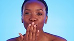 Face, beauty and black woman blowing kiss in studio for wellness, skincare and pamper on blue background. Makeup, beauty and portrait of girl model relax with luxury, grooming and cosmetic care