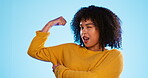 Wink, arm and bicep with a black woman joking in studio on a blue background for fun or humor. Playful, strong and muscle with an attractive young female comic flexing while winking or laughing