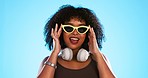 Trendy black woman face isolated on blue background for beauty, cosmetics and fashion of gen z lifestyle. Confident african american person or model with cool sunglasses and headphones for summer