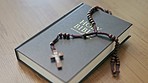 Religion, holy bible and rosary on a table for prayer, religious study or church service. Christian, faith and spiritual book with a crucifix for reading, worship or praying to god for compassion.