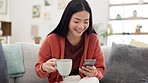 Coffee, cellphone and Asian woman on a sofa browsing on social media, mobile app or the internet. Relax, technology and female drinking a cappucino while scrolling on her phone in living room at home