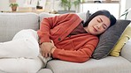 Pain, cramps and Asian woman on couch, stomach and suffering with sickness, illness and constipation. Japan, female and lady on sofa, period and medical issue with tummy, menstrual cycle and problems