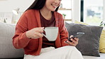 Closeup, coffee and woman on couch, smartphone and typing with connection, social media and happiness. Zoom, happy female on sofa with tea and cellphone in living room, communication or search online