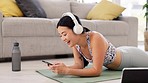 Asian woman, laughing and phone video watching of a young gen z person on a yoga mat. Living room, home and headphones of a female on a fitness break from pilates exercise while on a mobile app