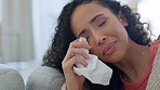 Crying face, depressed and sad woman on a living room sofa with a tissue and mental health problem. House, anxiety and suffering of a mixed race female on a home lounge couch with tissues in distress