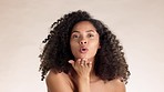 Skincare, face and woman blowing a kiss in the studio with a natural, beauty and self care routine. Cosmetic, happy and portrait of female model from Mexico with intimate gesture by brown background.