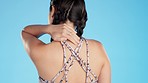 Sports injury, rear view and woman with back pain in studio for ache, muscle or arthritis on blue background. Behind, spinal and girl with injured neck issue, fibromyalgia or osteoporosis problem 