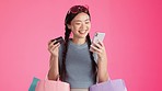 Shopping notification, phone and Asian woman with credit card for clothing sales purchase online. Isolated, pink background and fashion app with a young, female and gen z model with deal and sale bag