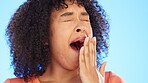 Yawning, tired and face of woman in studio feeling sleepy, fatigue and bored on blue background. Female model covering mouth with hand to yawn for nap, lazy break to sleep and exhausted from insomnia