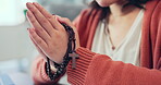 Christian woman, rosary and hands praying in home of spiritual faith, holy gospel and worship God. Closeup female, prayer beads and cross for religion, mercy and praise lord of jesus, heaven or peace