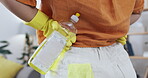 Woman, back and hands with detergent for housekeeping, spring cleaning or disinfection in living room at home. Rear view hand of female cleaner holding bottle of chemical sanitizer for germ removal