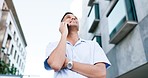 Phone call, happy and casual man in a city, relax and smile while enjoying day off outdoors against building background. Smartphone, conversation and young indian guy walking, free and calm in London