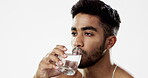 Man drinking water, hydration and health with serious face and glass in hand isolated on white background. Thirsty Indian male in studio, h2o and mineral with healthcare, wellness and mockup space