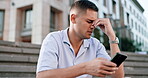 Phone, bad news and regret with a man in the city, city on steps while reading a negative text message. Sad, problem and 5g mobile technology with an unhappy young male feeling bad in an urban town