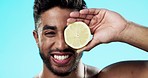 Skincare, lemon and face of man in studio for beauty, wellness and citrus treatment on blue background. Fruit, facial and portrait of indian guy model relax with organic, anti aging or skin cosmetics