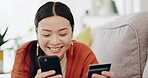 Asian woman, credit card and phone relaxing on her sofa online shopping, ecommerce and fintech easy payment. Young person in China typing bank information on cellphone for finance transaction at home