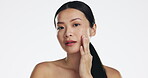 Skincare, asian woman and touch face in studio for beauty, dermatology or cosmetics on white background. Female model, portrait and facial aesthetic glow of shine, laser transformation and wellness