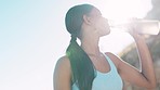 Runner, woman and drinking water in nature after fitness, running or morning cardio workout. Bottle, relax and thirsty indian girl drinking during workout, run or endurance performance outdoors