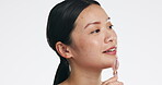 Asian woman, roller and face for skincare beauty, cosmetics or dermatology and anti aging against a white studio background. Happy female model rolling skin for facial treatment, health and wellness