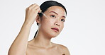 Asian woman, face and oil serum for beauty, facial skincare or dropper of hyaluronic acid in studio. Female model, cosmetics product and liquid collagen of glow, shine or thinking on white background