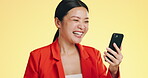 Winner, success celebration and Asian woman with phone in studio isolated on a yellow background. Surprise, fist pump or happy female with mobile to celebrate after winning lottery prize or good news