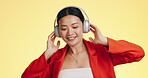 Dance smile, music headphones and woman in studio isolated on a yellow background. Technology, podcast or happy Asian female streaming, listening and dancing to radio, song and audio, sound and album