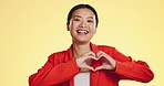 Smile, heart in hands and face of Asian woman on yellow background for love, support and charity mockup. Emoji, hand gesture and portrait of happy girl in studio with shape for care, trust and kind