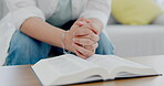 Bible, prayer and hands of a woman in house reading a book about God, Jesus Christ and worship. Female person at table in house to read holy books, pray and praise in Christian religion or faith