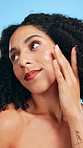 Moisturize, beauty and face of a woman with oil isolated on a blue background in a studio. Happy, cosmetics and portrait of a girl applying a moisturizing serum for facial glow, care and treatment