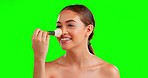 Brush, makeup and face of woman in studio for beauty, glamour and cosmetics on green screen background. Nose, tool and powder by girl happy, smile and relax with makeover, treatment and foundation