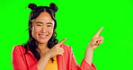 Happy asian woman, pointing and green screen for product placement, marketing or advertising against a studio background. Portrait of female smile showing point of advertisement, news or notification