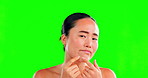 Asian woman, face and squeeze pimple on green screen in skincare for dermatology against studio background. Portrait of female with facial breakout, blackhead or grooming for acne treatment on mockup