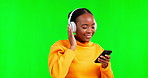 Green screen, headphones and black woman listening to music using phone and streaming online, internet or mobile app. Happy, excited and female person enjoying audio or radio isolated in studio