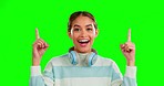 Green screen, gen z woman and pointing up with smile, mockup or product placement info on chromakey background. Announcement, information or advertising space, happy student in studio with headphones