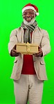 Christmas, present and man in a studio with green screen with a santa hat for a holiday event. Happy, smile and portrait of African male model with a xmas gift isolated by chroma key background.