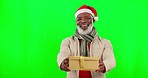 Christmas, present and man in a studio with green screen with a festive hat to celebrate at an event. Happy, smile and portrait of an African senior male model with xmas gift by chroma key background