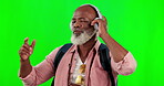 Black man, dancing and music headphones on green screen while carefree and content. African senior male dance on a studio background with mockup space and backpack listening to audio, sound and radio