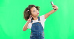 Silly little girl, selfie and peace sign on green screen with goofy facial expressions against a studio background. Female child or kid making funny face with hand sign for photo or vlog on mockup
