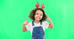 Happy, Christmas and thumbs up with girl in studio for holiday, festive and agreement. Approval, yes and like with child and deer headband on green background for satisfaction, smile and good news
