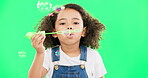 Children, bubble wand and a girl on a green screen background in studio playing with her toys. Kids, development and motor skills with a cute little female child blowing bubbles on a chromakey mockup