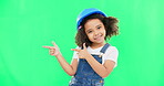 Kids, construction and a girl on a green screen background in studio pointing at building space. Children, architecture and design with a cute female child engineer wearing a hardhat on chromakey