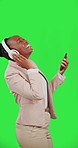 Black woman, dance with smartphone and headphones on green screen, listen to music with fun and rhythm. Professional female with online streaming, tech and radio with freedom on studio background