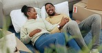 Black couple, relaxing and moving in new home on floor by living room sofa together with boxes. Happy African American man and woman lying in lounge for real estate, mortgage or property relocation
