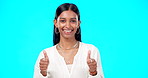 Thumbs up, excited and success by woman with hand gesture for approval isolated in studio blue background. Emoji, face and portrait of Indian female with fashion, perfection and support review